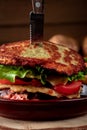 Macro view homemade burger made with hashbrown potatoes, salad, beef patty, cheese, tomatoes, concept of menu for restaurant in Royalty Free Stock Photo