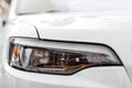 Macro view of modern white car xenon lamp headlight, bumper. Exterior of a modern car