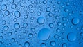 Macro view of numerous blue water droplets on a clear surface creating patterns Royalty Free Stock Photo