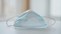Macro view of a single disposable surgical mask resting on a clean table surface Royalty Free Stock Photo