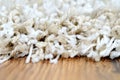Macro of white shaggy carpet on brown wooden floor Royalty Free Stock Photo