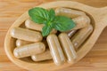 Macro of wooden spoon full of herbal medicine in clear capsules, ideal for Homeopathic remedies Royalty Free Stock Photo