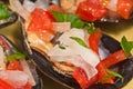 Macro, of a yellow bowl of freshly picked, local, steamed mussels on half shell with sliced onion, tomato and garlic