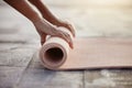 Macro of yoga, floor and woman hands with mat after exercise in gym, home or patio. Girl roll up gear after training