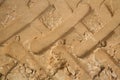 Macrophoto of a fragment of an unpaved sandy-loamy road with traces of elements of the tread of the large wheels of the tractor.