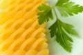 Macrophotography of raw fusilli and fresh parsley leaf on a pastel green background. Durum wheat pasta. Ingredient for healhy