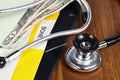 Macros shot of stethoscope on wood with American currency and papers.