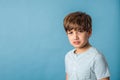 A mad angry pre-teen tween boy from the shoulders up on a muted blue backdrop