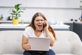 Mad screaming talking on the phone young fat girl working on laptop sitting on the sofa at home with the kitchen on Royalty Free Stock Photo