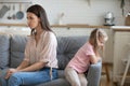 Mad young mom and little daughter sit separately after fight