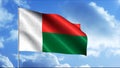 Madagascar flag waving in the wind on the background of blue cloudy sky, seamless loop. Motion. Colorful abstract flag Royalty Free Stock Photo