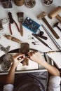 Made with love. Vertical photo of female jeweler`s hands polishing a silver ring with grinding machine