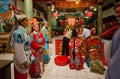 Made-up actores of Chinese opera in vintage costumes praying inside colorful Buddhist temple in old style