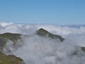 Madeira Mountain Peak Above the Clouds - Single, green, conical volcanic peak emerging from a low blanket of rolling white clouds Royalty Free Stock Photo