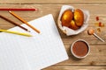 Madeleine cookie or French sponge cake alongside a school book, pencils, lollypop, candies and hot chocolate on wood background