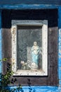Madonna statue in the window of old wooden cottage