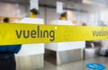 Yellow retractable belt barrier with grey Vueling airlines logo