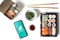 Madrid, Spain, February 09, 2021: Phone with Deliveroo app on a white table with sushi food in take-away containers