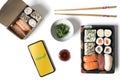 Madrid, Spain, February 09, 2021: Phone with Glovo app on a white table with sushi food in take-away containers. Take-away food,