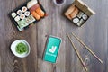 Madrid, Spain, February 09, 2021: Phone with Deliveroo app on a wooden table with sushi food in take-away containers