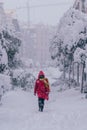 Madrid Spain - January 2021: a girl with a red coat who looks like little Red Riding Hood walks in a street covered in snow due