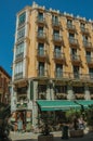 Old building with eatery and people walking on a street of Madrid