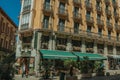 Old building with eatery and people walking on a street of Madrid