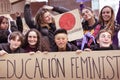 Group of teenage girls with painted faces holding a banner that says `Feminist Education`during the manifestation of Women`s Day