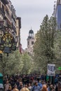 People walking along blooming cherry trees from Plaza de Isabel II along Arenal street (Calle del Arenal) to Puerta del Sol square