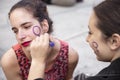 Young girl drawing on the face of another girl the feminist symbol during the manifestation of Women`s Day in Madrid, Spain