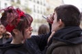 Young girl feminist drawing on the face of another girl during the manifestation of Women`s Day in the city center of Madrid