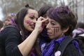 Young woman drawing on the face of another woman the feminist symbol during the manifestation of Women`s Day in the city of Madrid