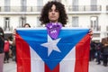 Young woman with serious face displays the flag of Puerto Rico during the manifestation of Women`s Day in the city of Madrid