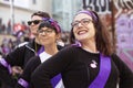 Young women dressed in scarves and violet sash smiling during the manifestation of Women`s Day in the city center of Madrid, Spain