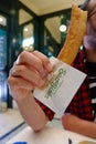 Madrid, Spain - May 15, 2021: Male hand holding traditional fried dessert porra churro in famous 100 years old cafe San Gines