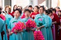 Women Participants in the Chinese New Year parade dressed in traditional light blue costume and carrying fans. In the neighborhood