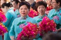 Women Participants in the Chinese New Year parade dressed in traditional light blue costume and carrying fans. In the neighborhood
