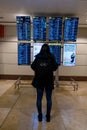 Madrid, Spain: November 15 2022. Young woman standing with her backpack looks at schedule on airport station. Themed public