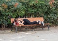 Madrid, Spain, October 7, 2019. Young girl lying on park bench in black jeans and top, head on her bag