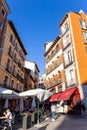 Pedestrian street in Madrid, Spain, with restaurants, cafes, shops, tables on a street and people.