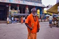 Madurai, India - November 02, 2018: An old man in orange hindu traditional wear walking with a stick in front of a hindu temple