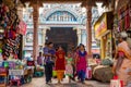 Madurai, Tamil Nadu / India: Indian family walks through an arch occupied by shops, with Meenakshi Temple
