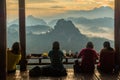 Tourists sitting in rural restuarant and having food while looking to morning view of mountain