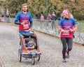 A young family with baby in a stroller is running a marathon. Active and healthy lifestyle. Leisure sports activities for people