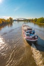 Magdeburg historical downtown, Elbe river, modern arch Sterne Bridge with coming a big cargo ship with a car, barge, in golden