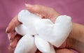 Image of white handmade fabric hearts in woman`s hands on pink background