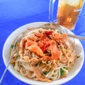 Magelang 20 September 2023 A white bowl containing chicken noodles on a green table and a glass of brown iced tea in the stall