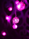 Magenta pink Rattan light balls garland on patterned wall. New Year`s garland. Christmas led lights on dark background. Blurred Royalty Free Stock Photo