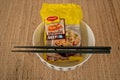 A package of instant noodles in a bowl with chopsticks.