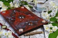 Magic book with decorated cover, old watches and cup on witch table